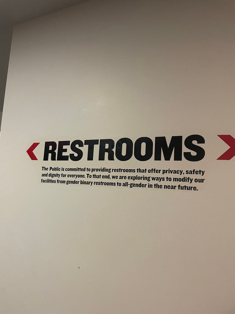 Entry way to the restrooms with writing that says The Public is committed to providing restrooms that offer privacy, safety, and dignity for everyone. To that end, we are exploring ways to modify our facilities rom gender binary restrooms to all-gender in the near future.